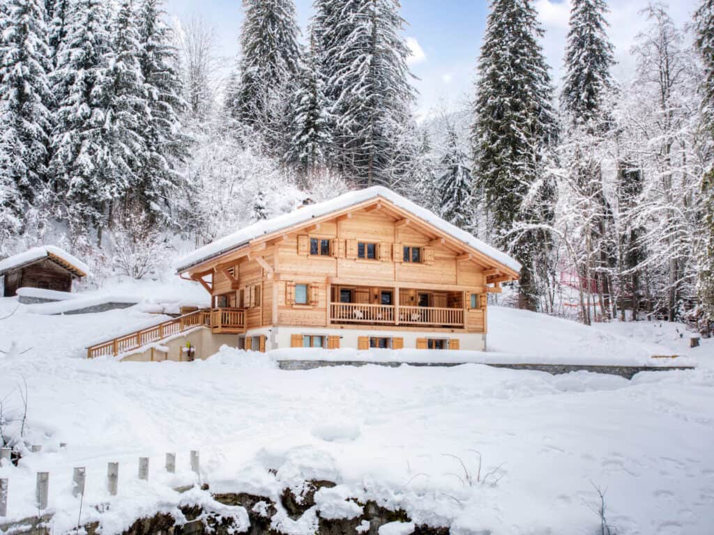 Chalet Riparian entouré d'une forêt enneigée.