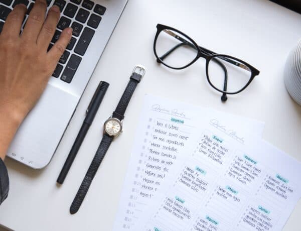 Une checklist est posée sur une table avec un ordinateur, une paire de lunettes et une montre