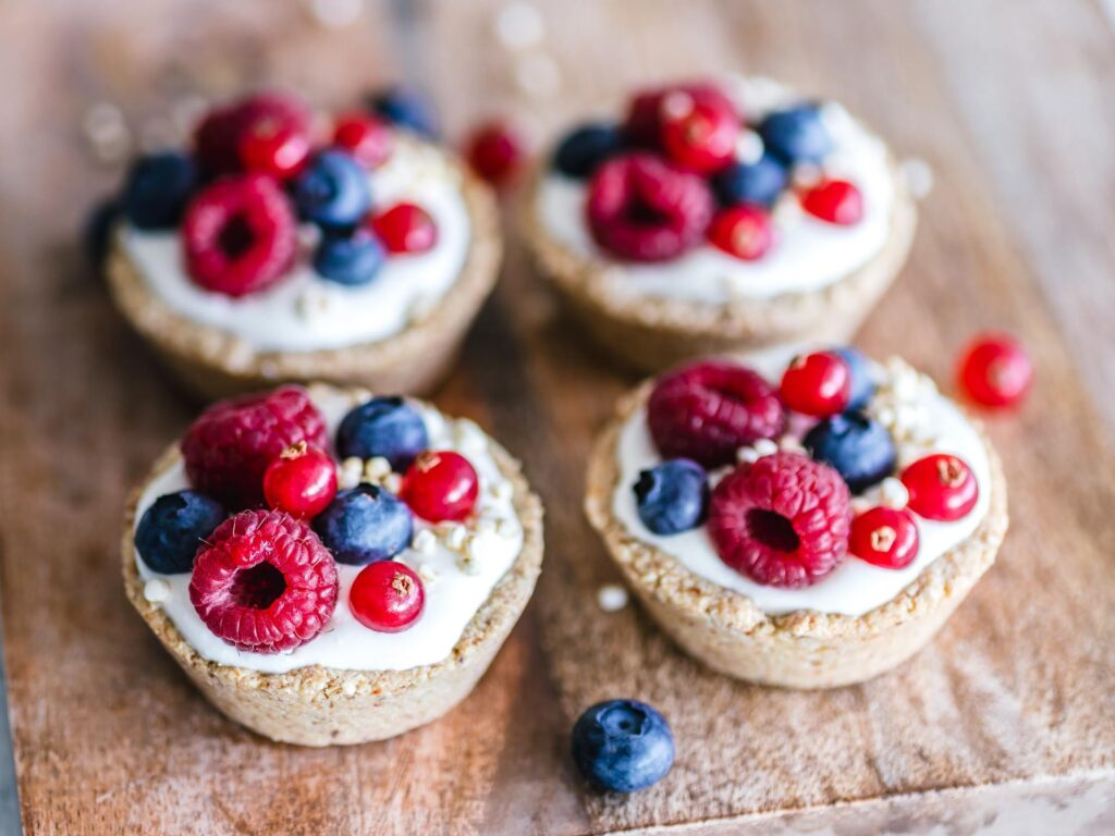 Four mixed berry tarts on a wooden board