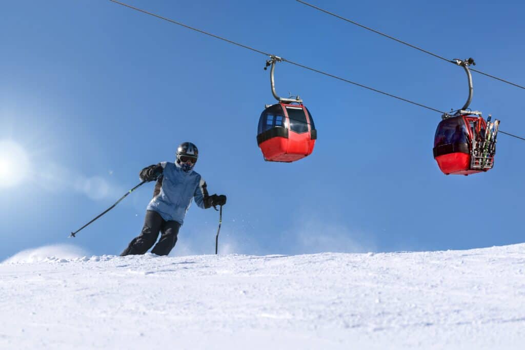 Skieur sur une piste et télécabines.