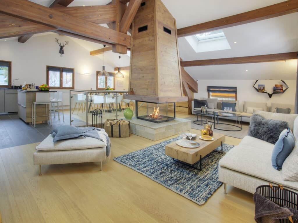 Un salon moderne et neutre avec une cheminée centrale et des éléments en forme de tête de cerf.