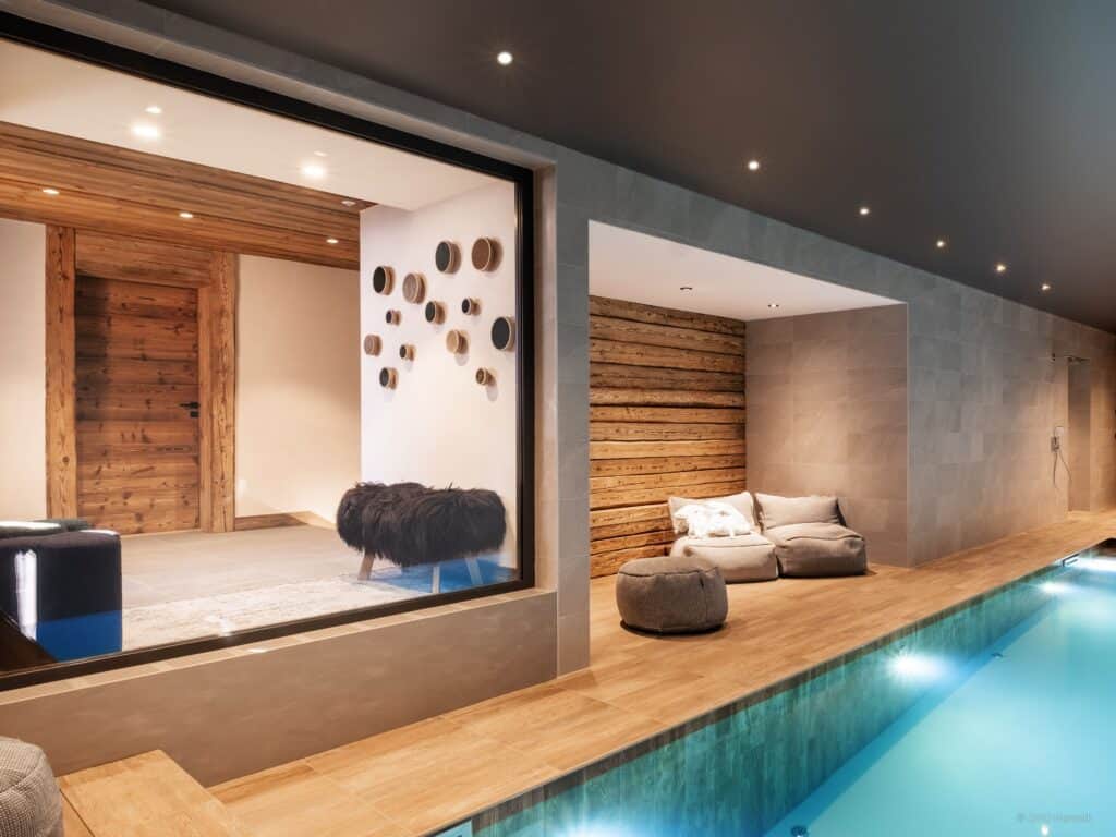 An image of a swimming pool with a large window looking into a corridor which features 3D circular wall art.