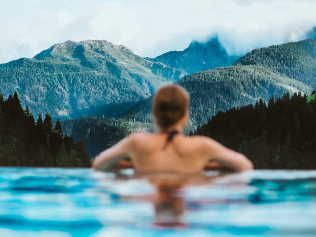 A woman admires the mountain view from a swimming pool