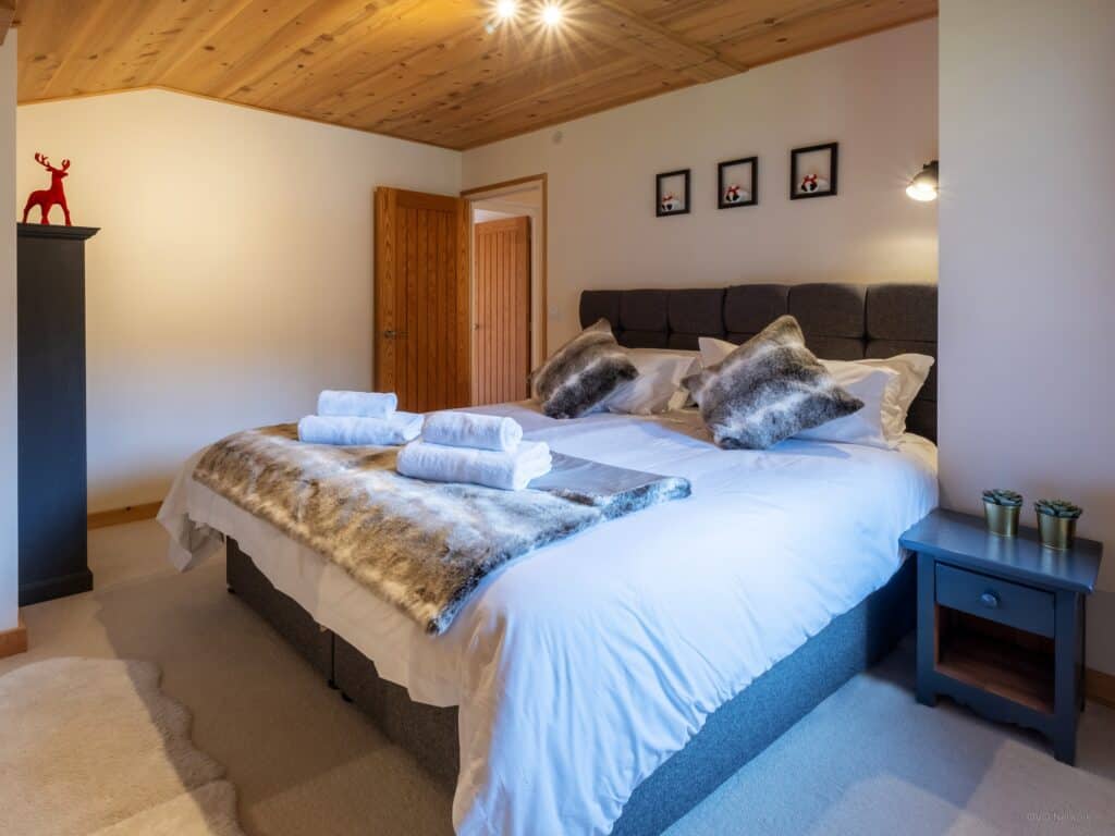 Faux fur cushions and throws on a double bed in one of the bedrooms at Chalet Bolay in Montriond