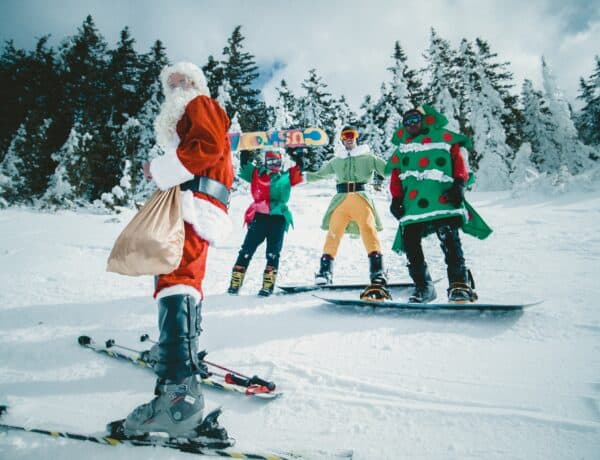 Plusieurs personnes en ski et snowboard, dont une en costume de Père Noël.