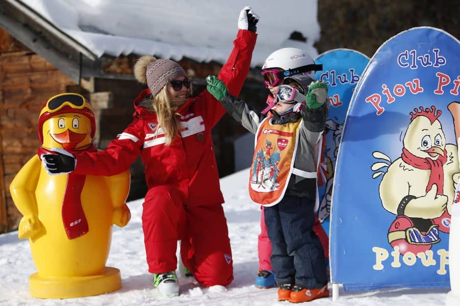 Une monitrice de ski apprenant à deux enfants à skier au club Piou-Piou.