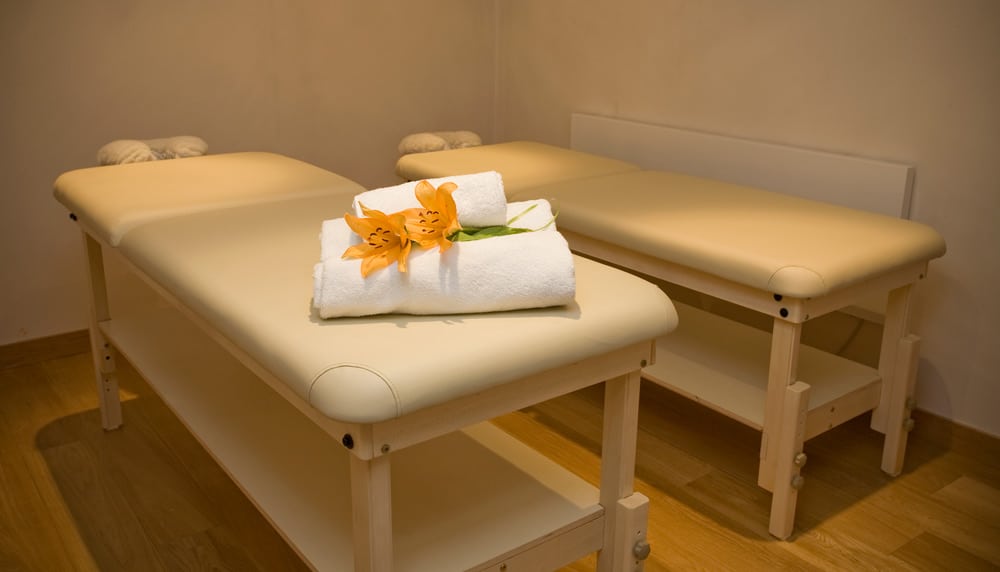 Salle de massage du chalet Preta avec deux lits de massage, et deux serviettes avec fleurs orange décoratives posées sur l'un des lits. 