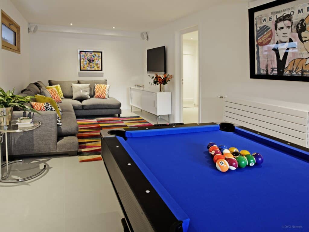 A bright blue pool table with large sofa in the background and TV screen.