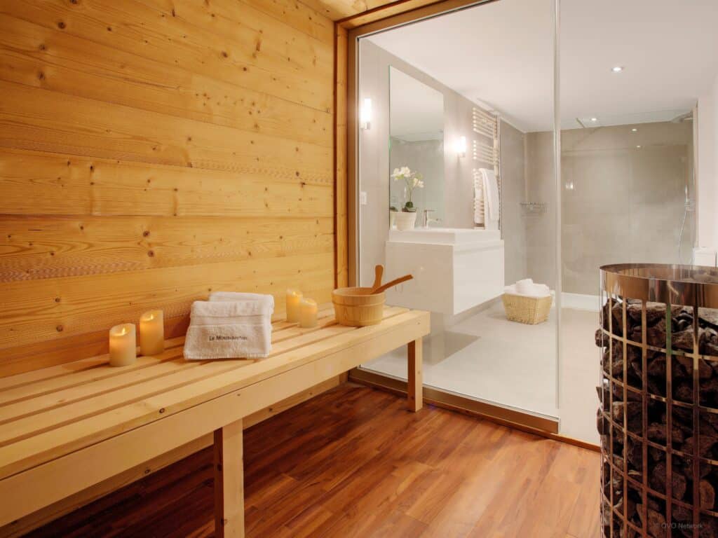 A bright sauna with water bucket and candles.
