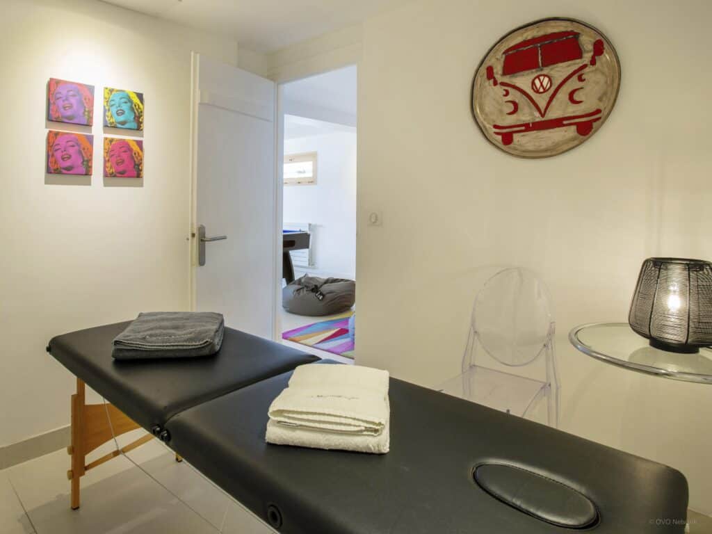 A massage table in a white room with bright artwork on the walls.