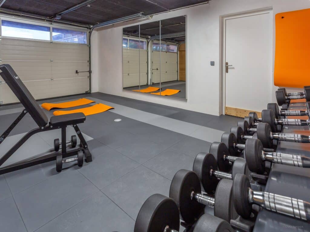 Salle de sport avec tapis de yoga, miroir et banc de musculation.