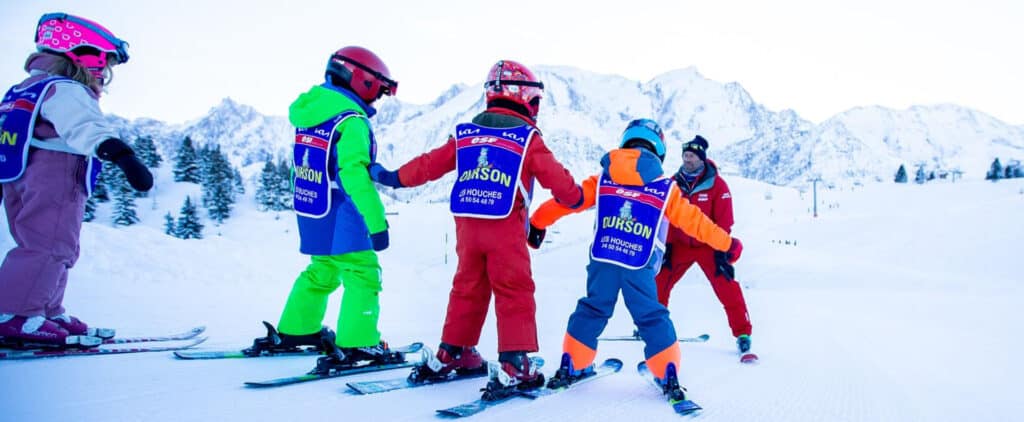 Enfants apprenant à faire du ski avec un moniteur de l'ESF dans les Alpes. 