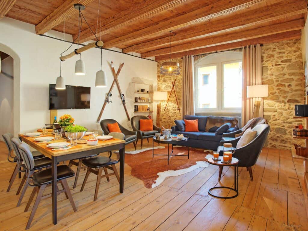 Un salon chaleureux avec des coussins orange et un sol en bois. 