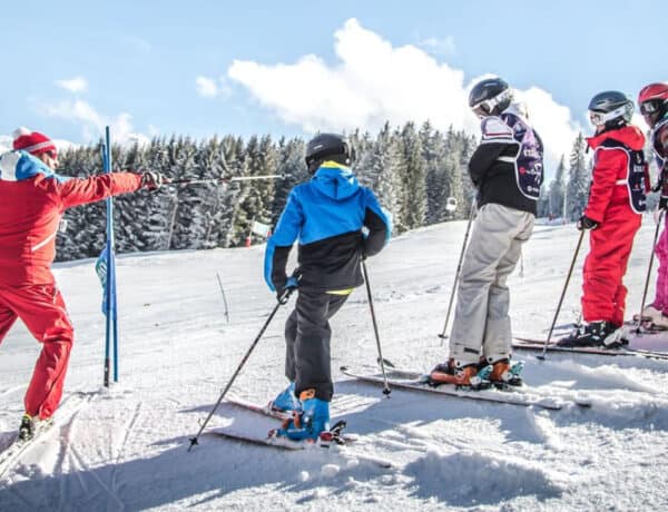 Enfants sur une piste de ski écoutant un moniteur.