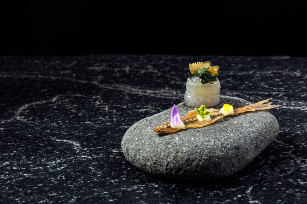 A fish dish is served with edible flowers
