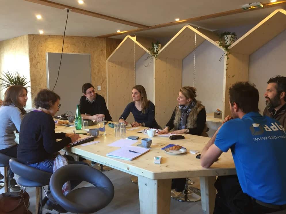 A group working in a shared office with wooden tables and leather seats in La Clusaz