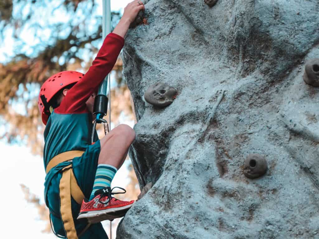 Un jeune garçon grimpe sur un mur d'escalade.
