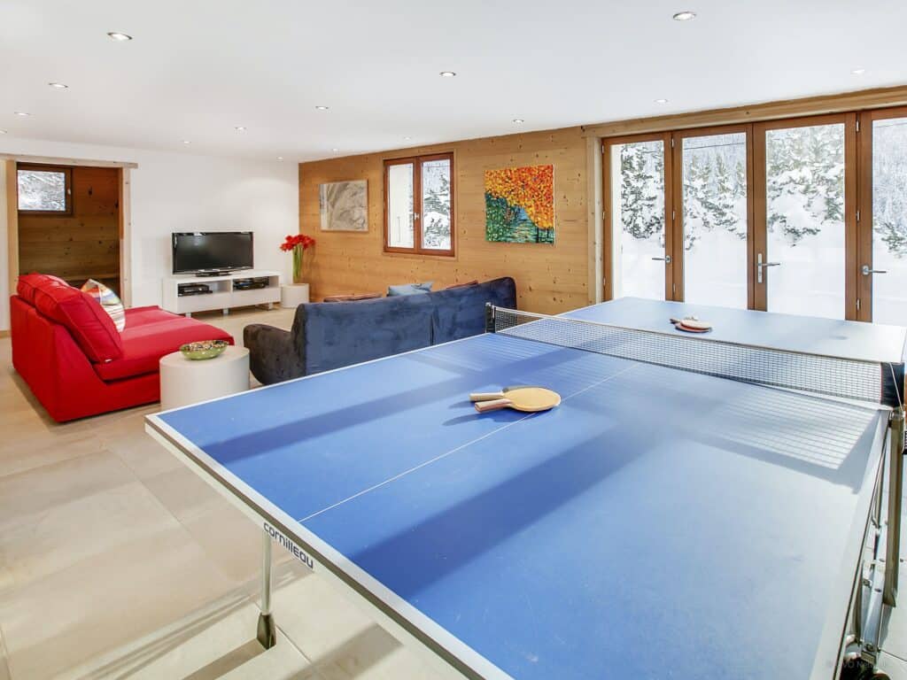 A large ping pong table with sofas and TV in background.