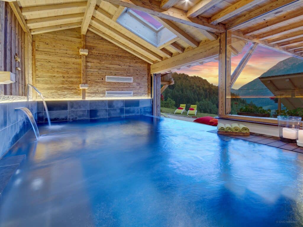 Chalet Ladroit indoor pool looking out onto a mountain view at dusk