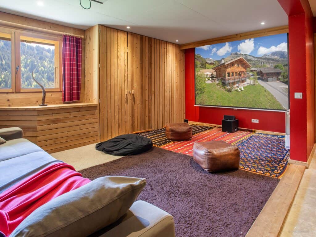 A red cinema room with poufs and fluffy rugs.