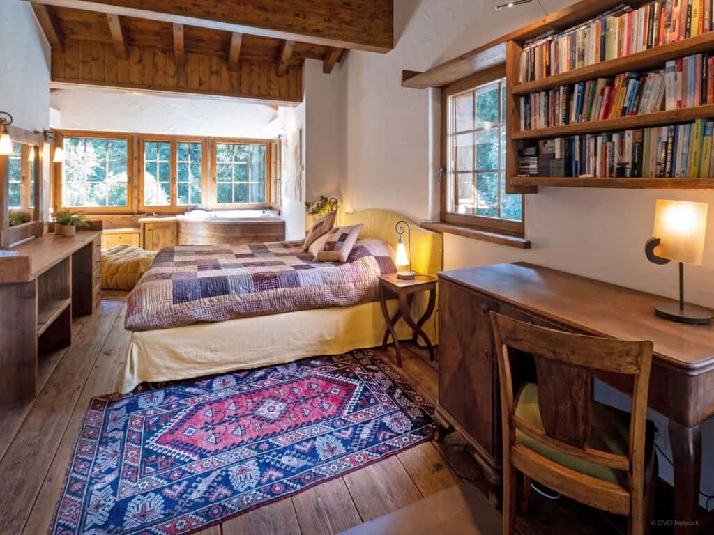 Bedroom with desk in corner below a bookshelf