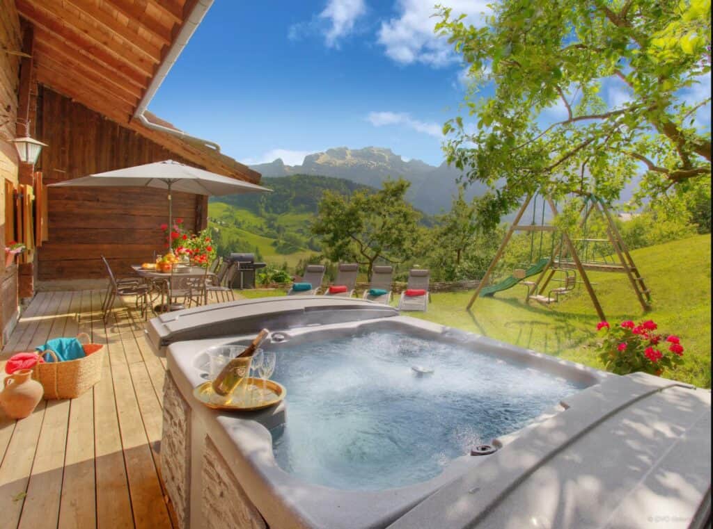 Outdoor hot tub with dining area and lush green garden