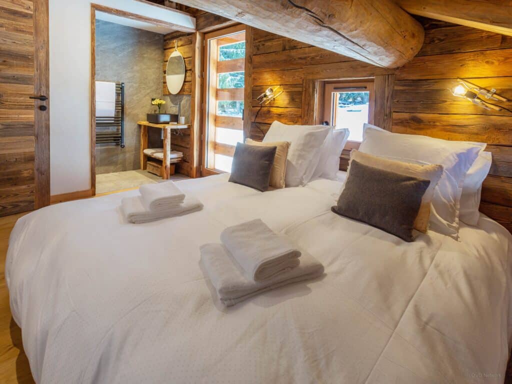 Natural wood in the bedroom, with white bed linen and an en suite bathroom