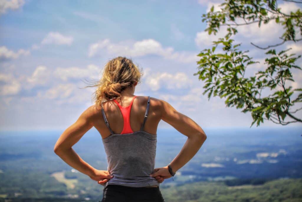 Une femme debout de dos observant le paysage montagneux. 