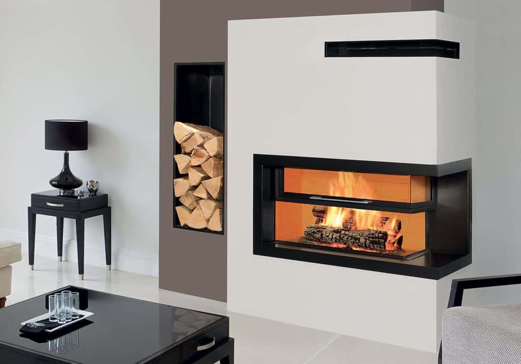 A fire burns in a modern corner fireplace with a built-in space for wood storage