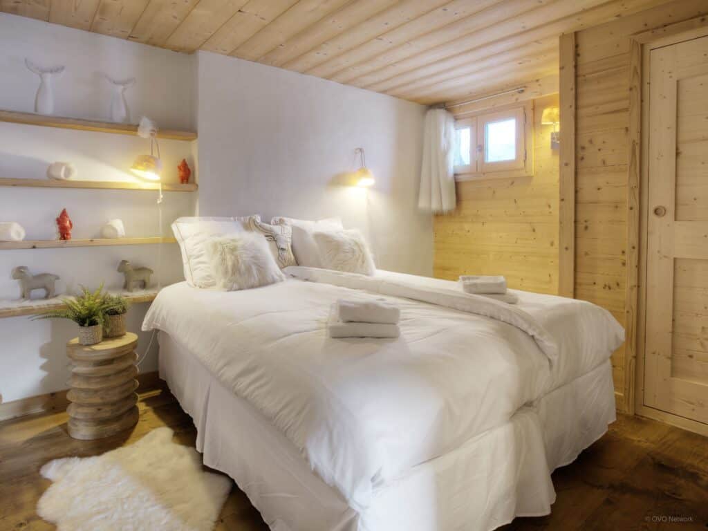 A neutral coloured bedroom with bedside lamps in a wooden chalet
