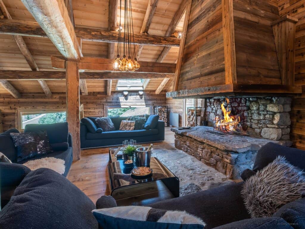 The living room at Chalet Victorina with dark blue sofas and a roaring open fire
