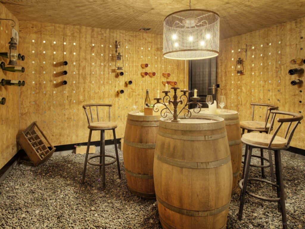 Une cave à vin avec des tonneaux en bois et des tabourets.
