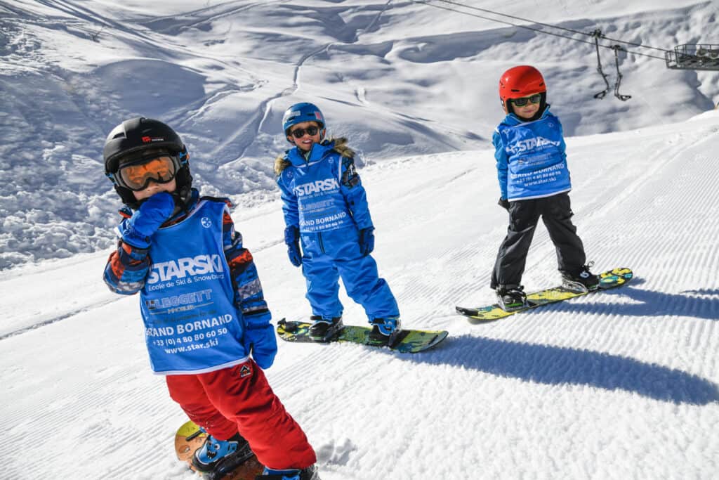 Three children on snowboards on a slope near Le Grand Bornand