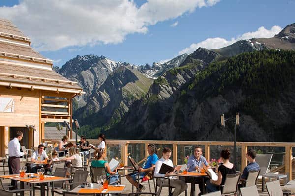 Une terrasse remplie de tables et de personnes en montagne