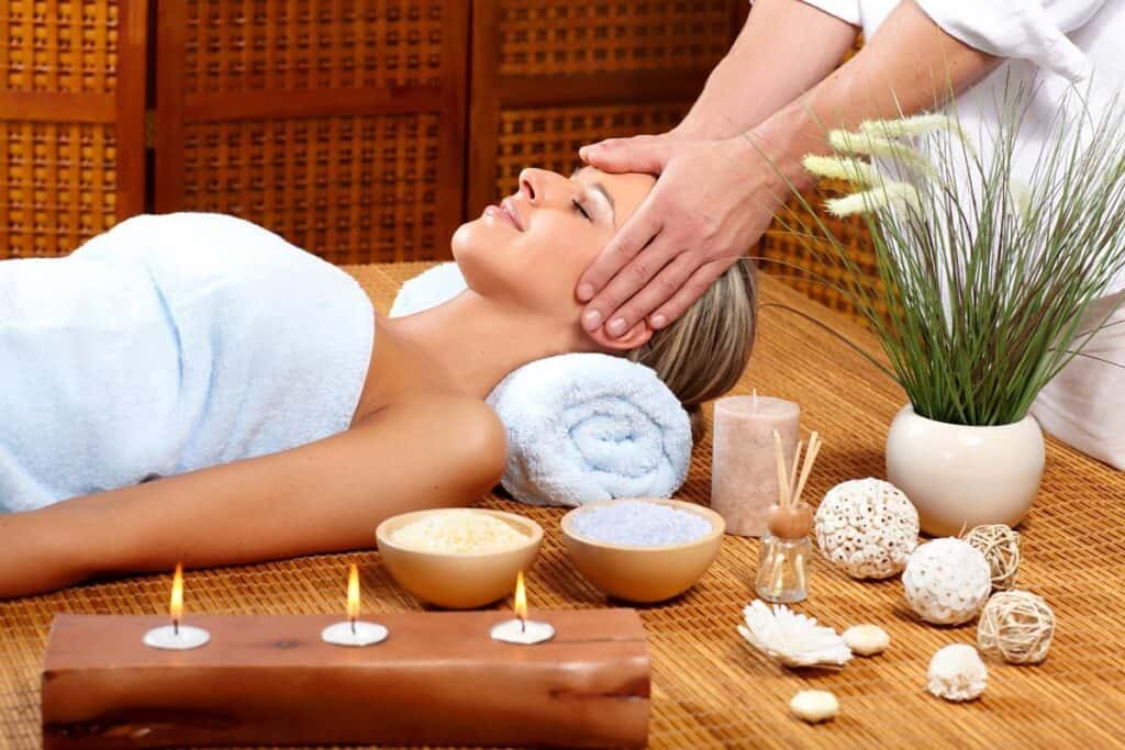 A woman enjoys a massage surrounded by candles