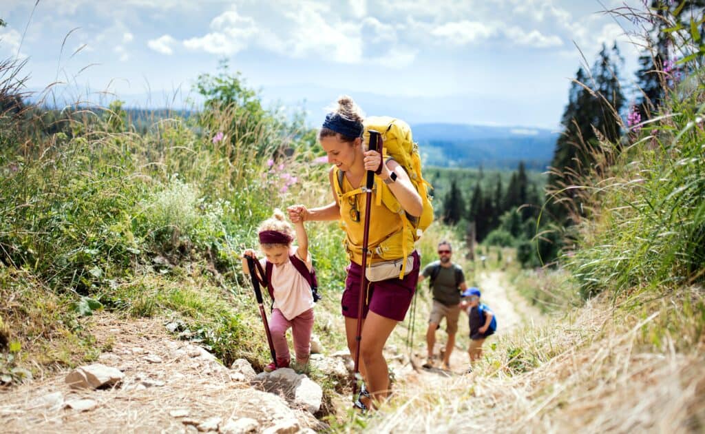 Parents and their two children hike through the mountains in summer