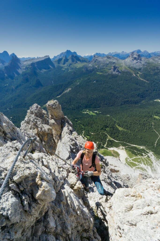 Une femme portant un haut rose faisant de l'escalade au soleil. 