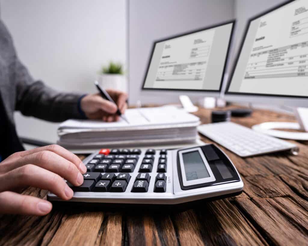 A man sits at his desk working out figures on a calculator