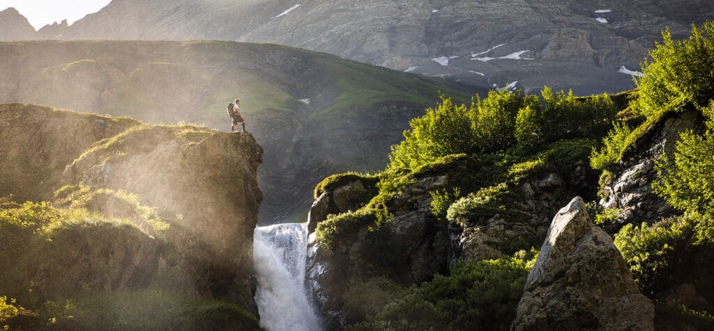 A hiker stops for a break near a mountain stream