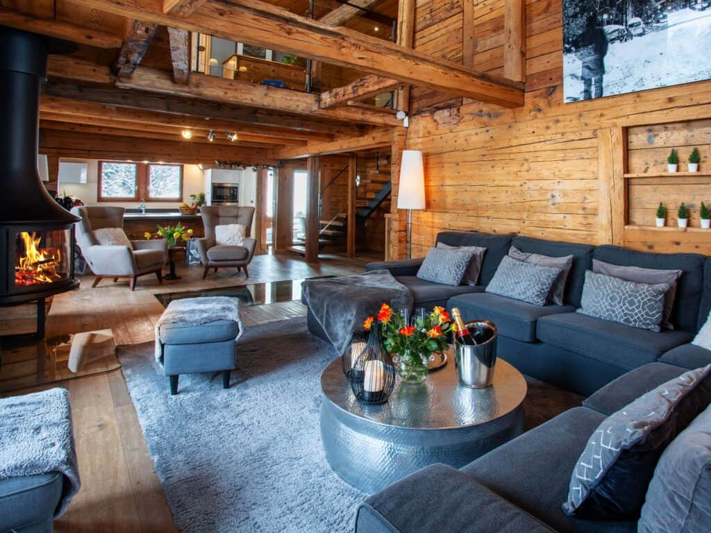 Le chaleureux salon du Chalet Colombine avec ses grands tapis, ses canapés recouverts de plaids et sa cheminée.