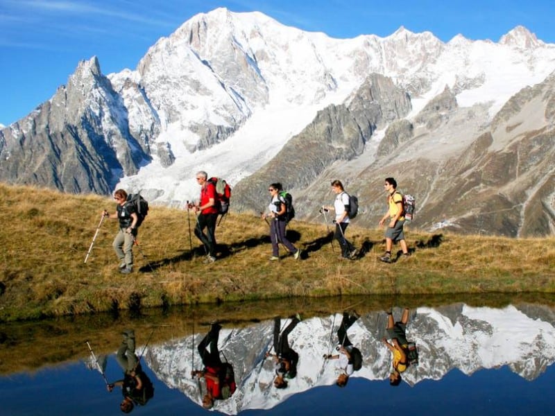 Five people walk with poles around Mont Blanc