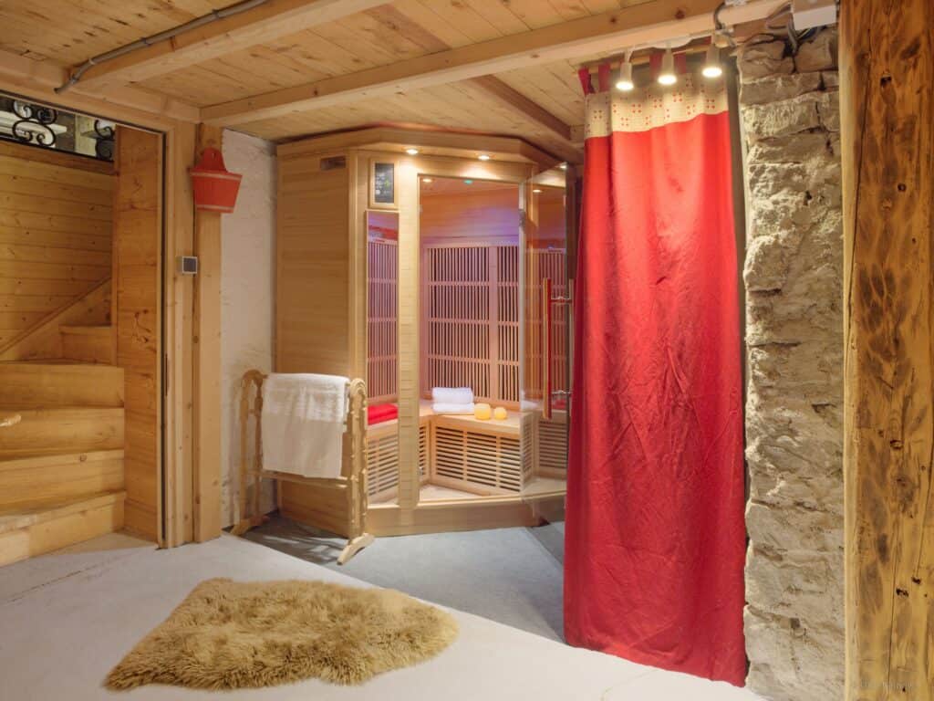 Cabine de sauna en bois du chalet Le Meridien Etale à la Clusaz, avec des serviettes de bain et des bougies.