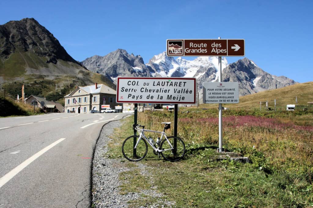 A cycle rests against a signpost at the top of a climb