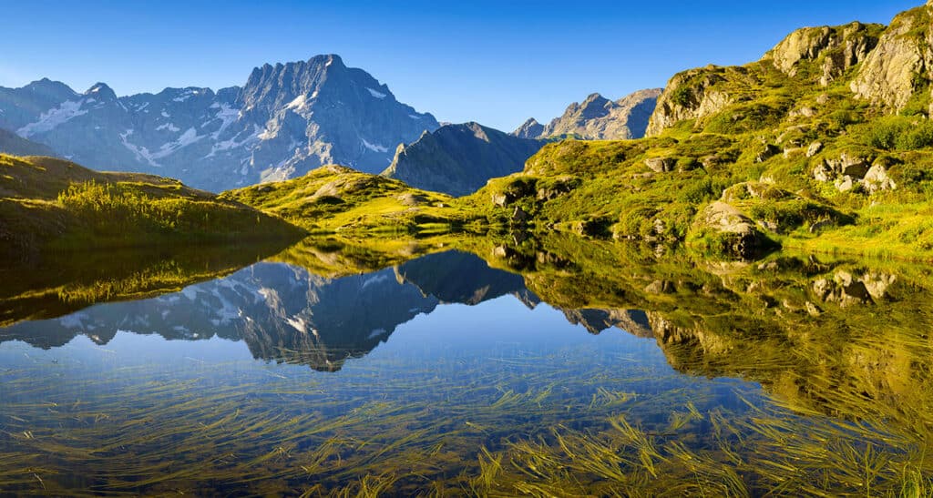 The surrounding mountains are reflected in an Alpine lake