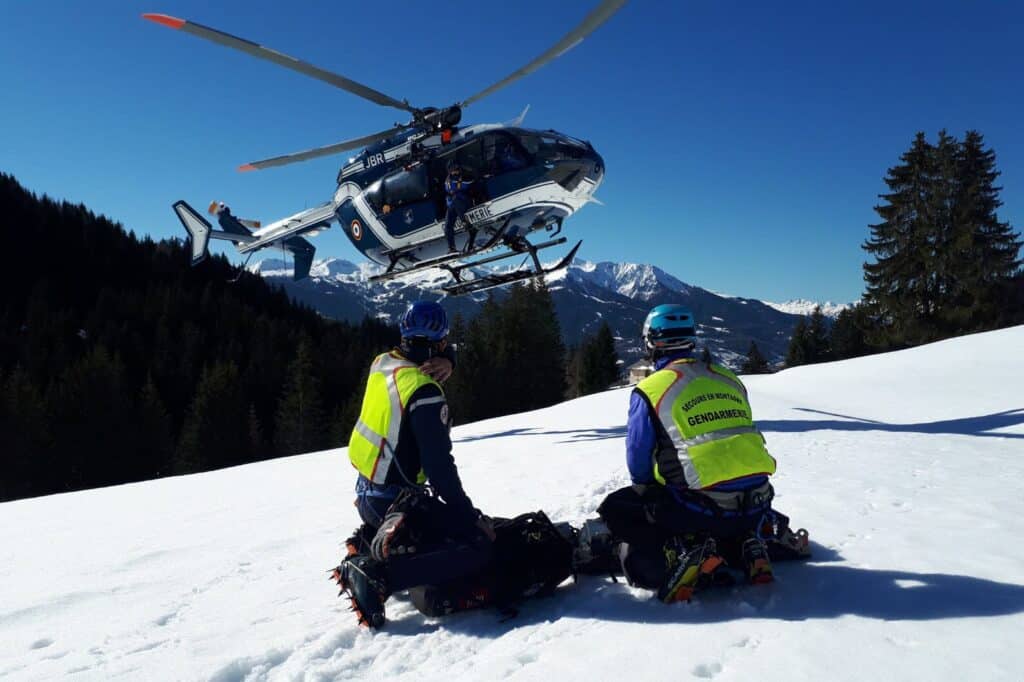 Two police officers attend a mountain rescue call while a helicopter hovers overhead