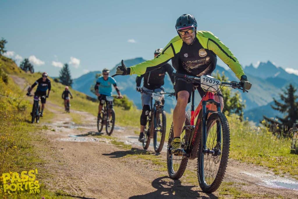 Un groupe d'hommes à vélo descendant une colline. Le premier homme se baisse et tend la main. 