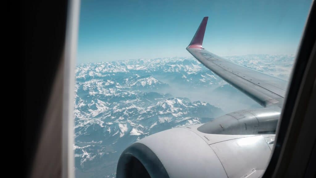 Vue d'une montagne enneigée depuis le hublot d'un avion.
