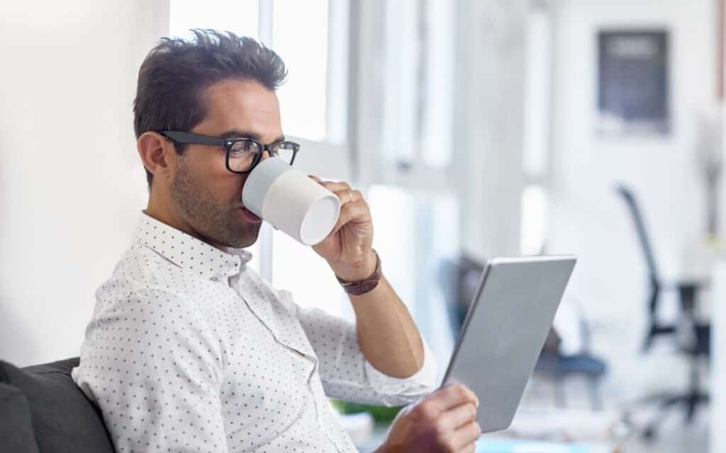 Homme avec sa tablette buvant un café.