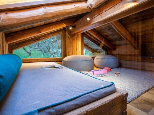 A games room under the eaves with a daybed and floor cushions