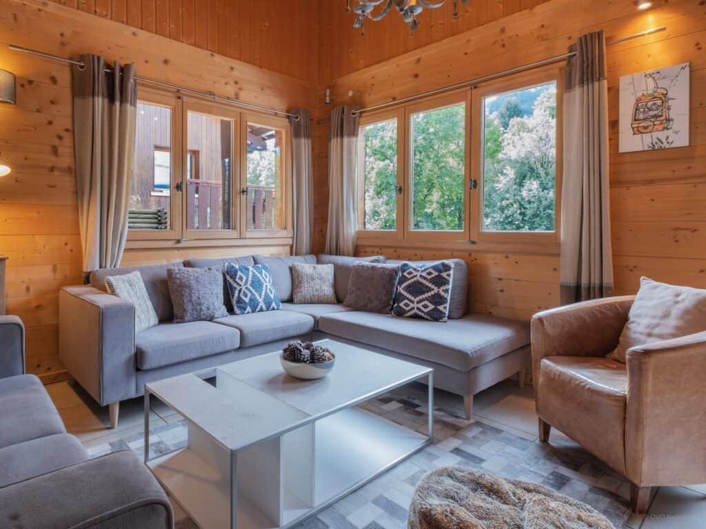 Two grey sofas and a chair in front of the windows in the living room at Chalet Bellanis 